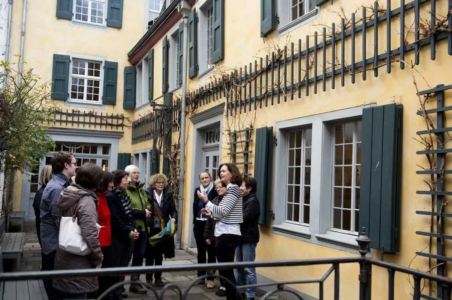 Im Museumshof vor dem gelb gestrichenen Hinterhaus, dem eigentlichen Wohnhaus der Familie Beethoven, steht eine Besuchergruppe und lauscht der Führerin.